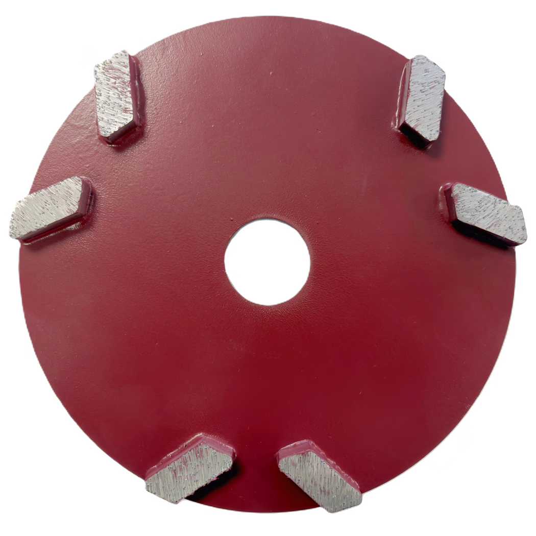 Derendinger_Dummy_187143_Frästeller_DS-Rhombus-V_2025.11 Gros plan d'une meule/disque circulaire en métal peint en rouge, cadrée de manière à occuper la moitié supérieure de l'image. Plusieurs segments rectangulaires métalliques argentés (segments diamantés) soudés sur la périphérie sont partiellement visibles ; cinq segments montrent leurs faces de coupe texturées et des traces d'usure légères. Un trou central circulaire apparaît près du centre de l'image. La peinture rouge du corps en acier présente une texture légèrement rugueuse et mate avec de petites imperfections de surface et des cordons de soudure autour des pieds des segments. L'arrière-plan est blanc, isolant l'outil. L'image met en valeur le contraste de matériaux entre l'acier peint et les surfaces brillantes et striées des segments, adaptée à une documentation produit, catalogue ou technique.
