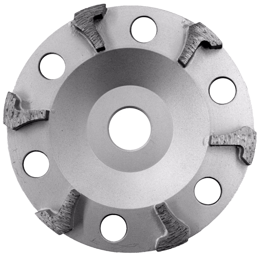 Gros plan en plongée d'une meule à godet diamantée circulaire. La roue métallique gris argent présente un centre conique peu prononcé et un trou de montage central. Sur la bride extérieure se trouvent huit orifices d'aération circulaires répartis régulièrement et six segments diamantés brasés avec des faces de coupe texturées, avec des soudures visibles et de légères traces d'usure. La surface est mate avec de fines marques d'usinage. L'outil sert à meuler et profiler le béton, la pierre et la maçonnerie. Éclairage doux et uniforme sur fond blanc.