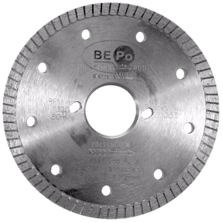 Un disque circulaire en métal à segments diamantés, avec plusieurs trous de refroidissement et un alésage central ; la lame gris argenté porte des inscriptions du fabricant et de légères traces d'usure, conçue pour couper carrelage, pierre ou maçonnerie.